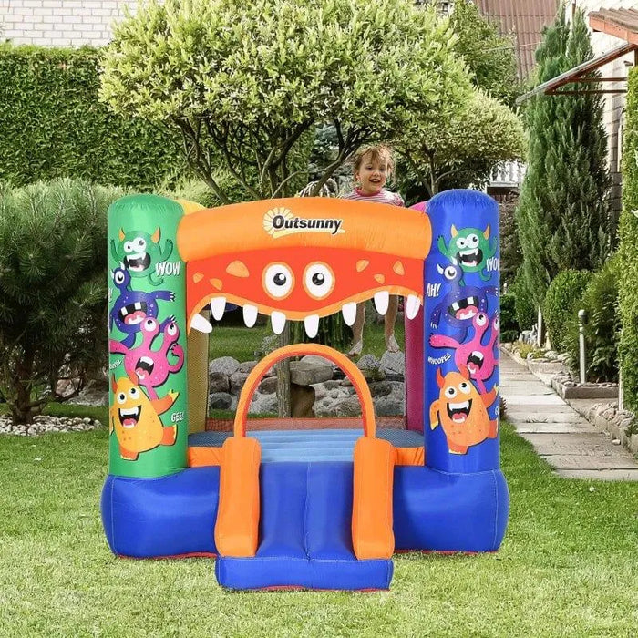 Outsunny monster inflatable bouncy castle with slide and cartoon designs in a garden