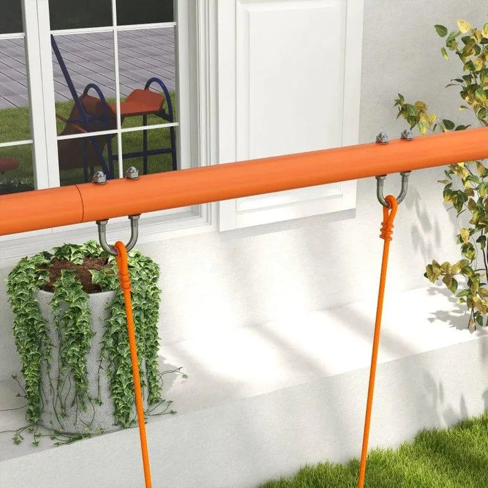 Orange swing set frame with ropes in a garden near a window and green plants