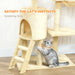Gray cat with green eyes scratching beige carpeted cat tree with ladder in room