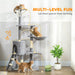 Multi-level gray cat tree with three orange cats playing, a green plant, and a food bowl in a bright room