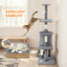Gray multi-level cat tree with scratching posts and hanging toys in bright room with jumping cat
