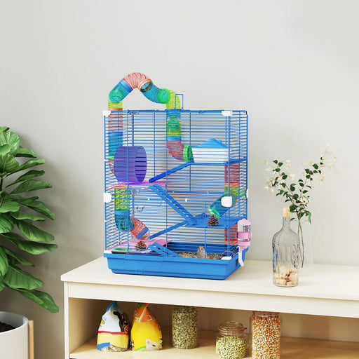 small blue metal hamster cage with colorful tubes, wheel, and hamster on a white table with plants nearby
