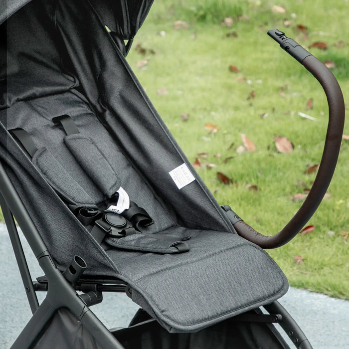 Close-up of a black stroller seat with a blurred grass background