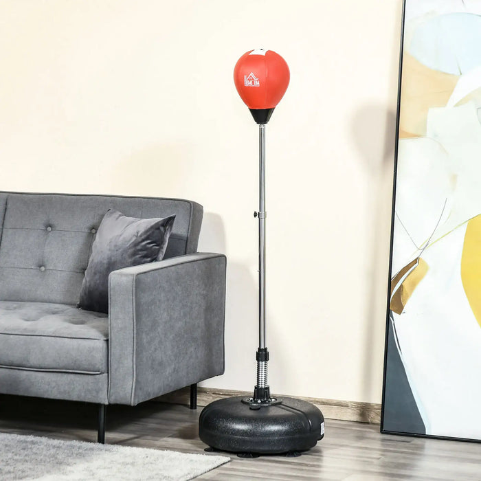 Adjustable red punching bag with black base next to a gray sofa and abstract wall art in living room