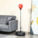 Adjustable red punching bag with black base next to a gray sofa and abstract wall art in living room