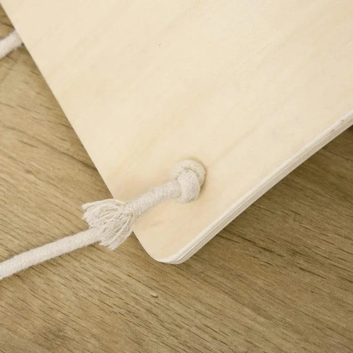 Natural beech wood wobble balance board with sturdy white rope on wooden floor
