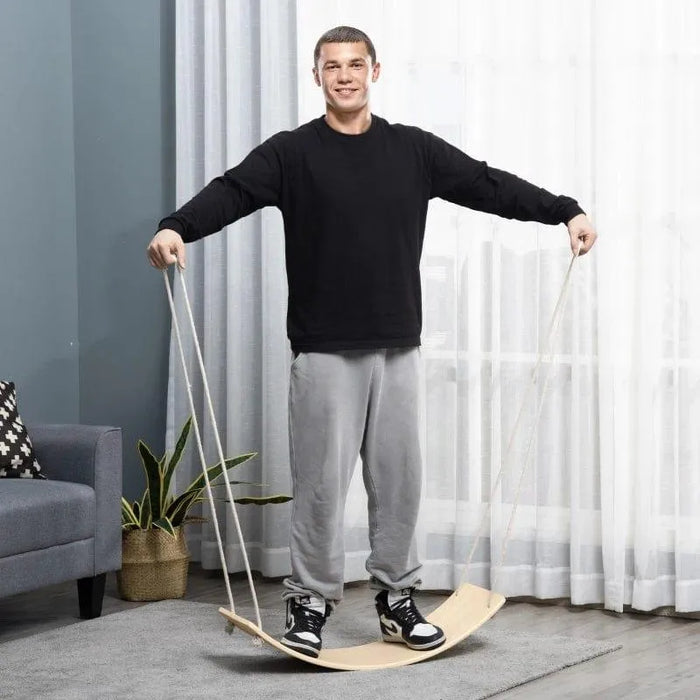 Man using natural beech wood wobble balance board with ropes in modern living room