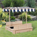 Natural wood sandbox with benches and navy striped canopy in a garden