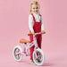 Child with pink balance bike featuring adjustable seat and lightweight metal frame