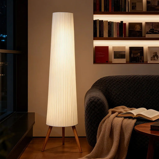 Tall floor lamp with a cylindrical shade in a living room setting.
