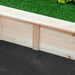 Close-up view of the corner of a wooden Outsunny raised garden bed with a bottomless design on a green grass background, featuring natural wood planks joined together and a black fabric lining underneath.
