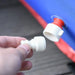 Hand attaching white valve piece to inflatable bouncy castle connector