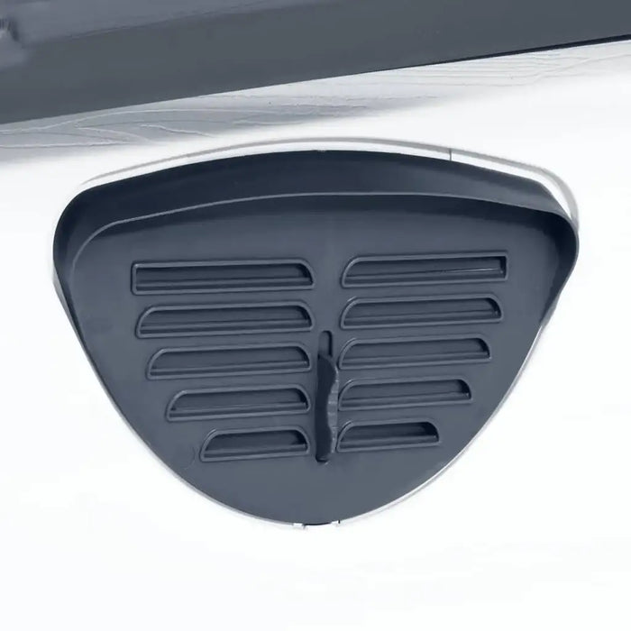 Close-up of a black ventilation vent on a grey outdoor dog house or kennel.