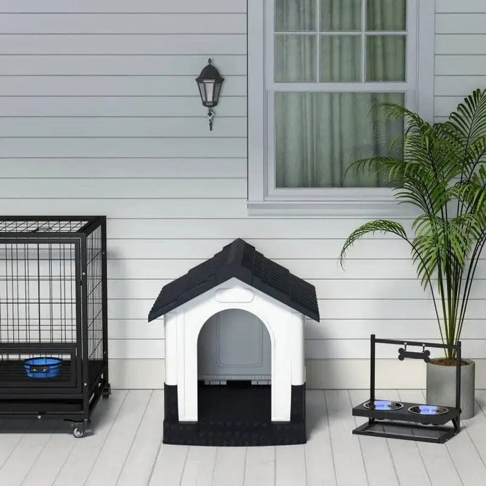 Outdoor plastic dog kennel with slanted roof and raised base beside pet crate and bowls