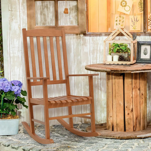Wooden rocking chair in a garden setting with a small table and decorative items.
