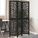 Black three-panel room divider with decorative cut-out patterns in a room setting.