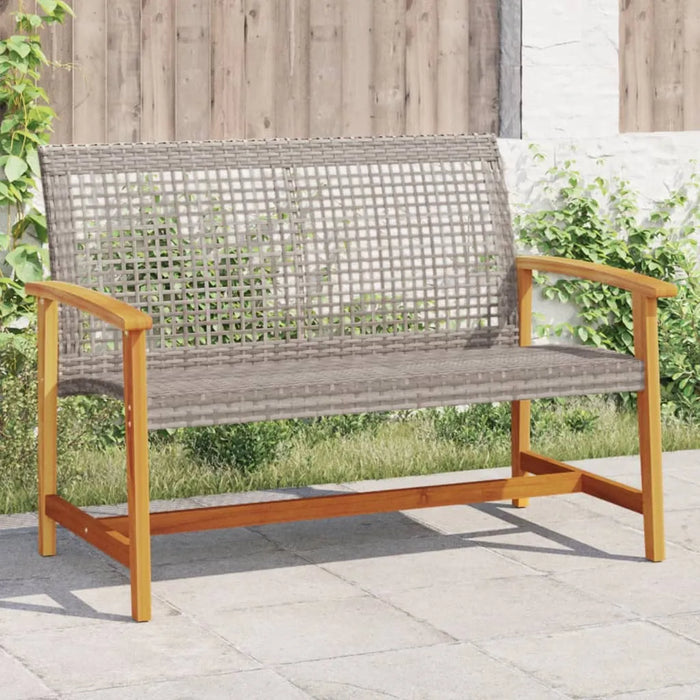 Grey PE rattan outdoor garden bench with wooden armrests on stone patio surrounded by greenery