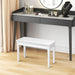 Dressing table with marble top and white bench in a room setting