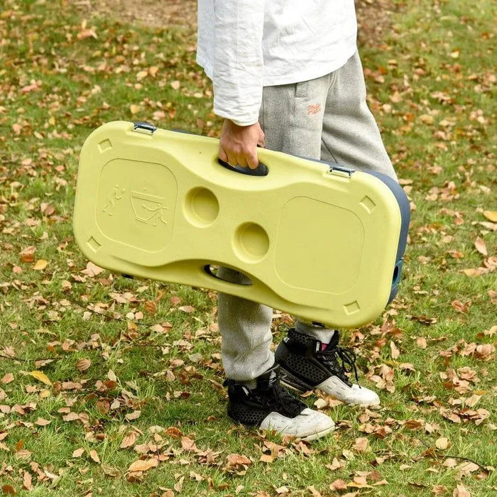 Person holding a yellow portable badminton set suitcase on grass outdoors