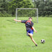 Boy kicking soccer ball toward portable 6ft x 4ft football goal net on grassy field