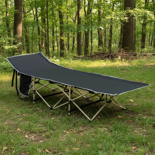 Black portable military folding camping cot with steel frame and side pocket in a forest