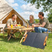 Three people enjoying outdoor camping with portable solar panel charging devices near a tent