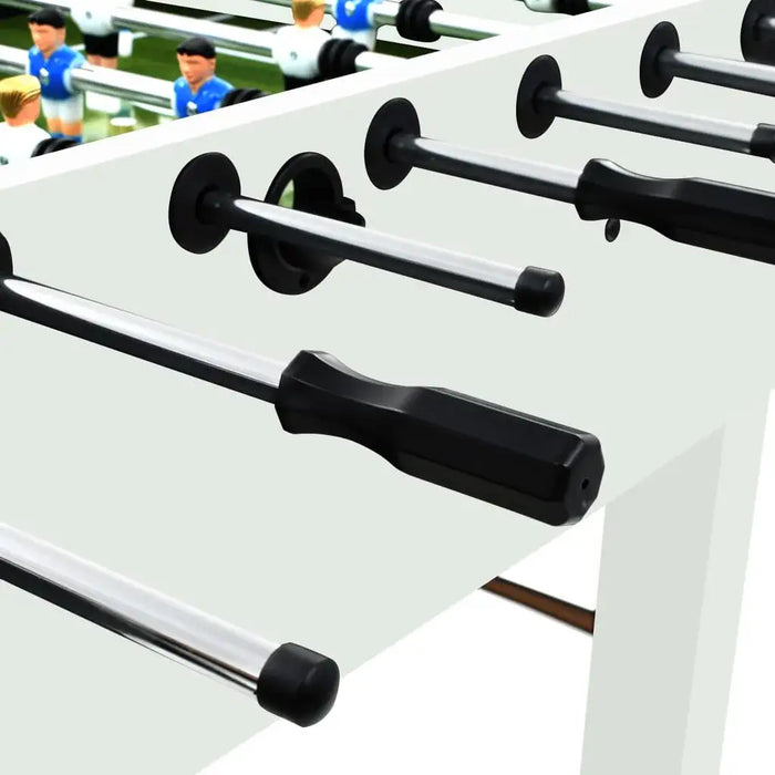 Close-up of white foosball table with black handles and player figures on green pitch
