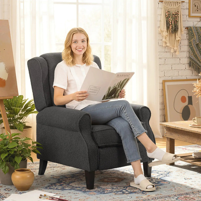 Woman sitting in a gray armchair reading a magazine in a cozy living room.