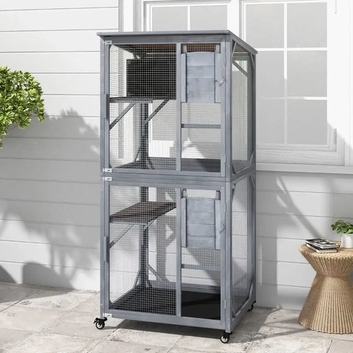 Large two-level gray outdoor wooden pet cage with mesh wire and wheels on patio