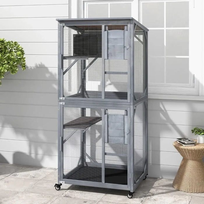 Large two-level gray outdoor wooden pet cage with mesh wire and wheels on patio