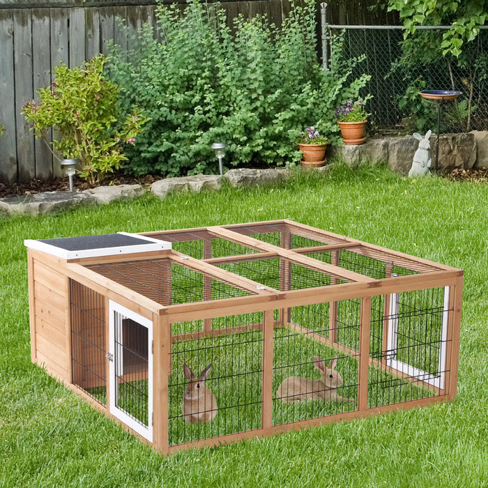 Wooden outdoor rabbit hutch with run and two brown rabbits on green grass in backyard garden