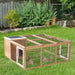 Wooden outdoor rabbit hutch with run and two brown rabbits on green grass in backyard garden