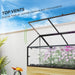 Raised garden bed with glass cold frame roof open for ventilation, growing pink and white flowers outdoors