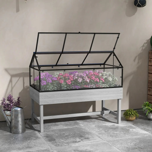 Raised garden bed with clear polycarbonate cover housing purple, pink, and white flowers on gray patio