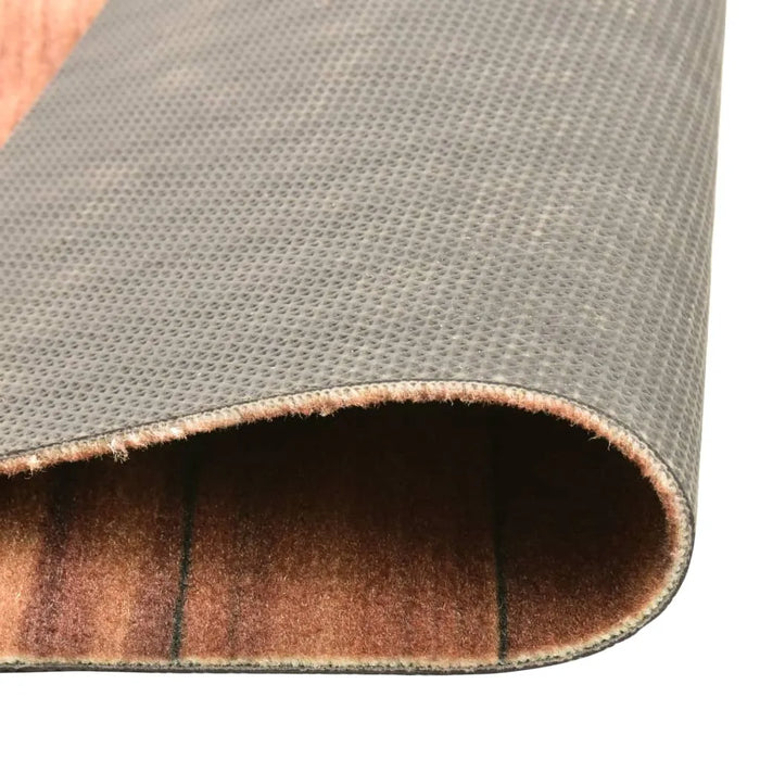 Close-up of a rectangular floor mat with textured black backing and brown velvet surface