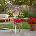 Red kamado grill with a wooden top on a white background
