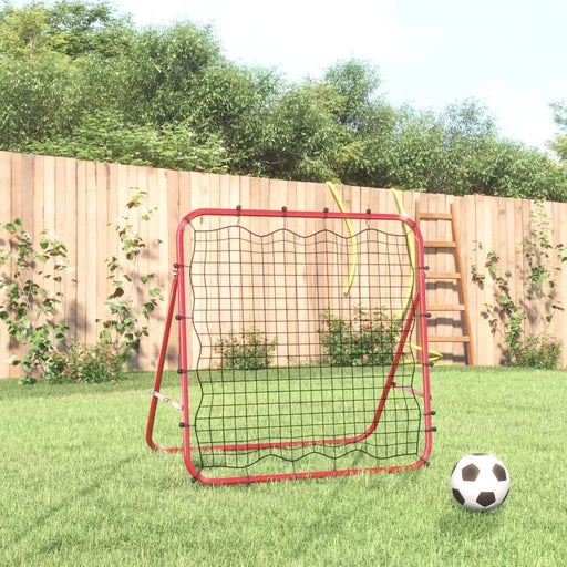 Red football kickback rebounder with steel frame and net on grass, soccer ball in front