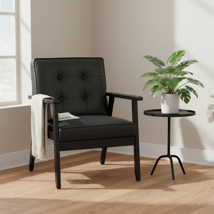 Black armchair with a small table and plant in a room with a window.
