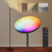 Colorful floor lamp with remote control on a wooden floor against a beige wall.