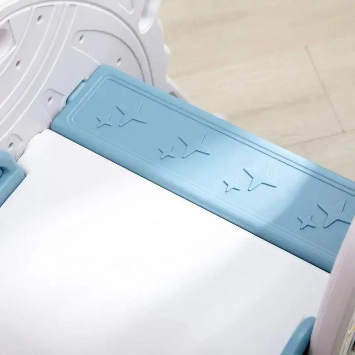 Close-up of blue and white rocket-themed toddler slide with embossed star decals, indoor setting
