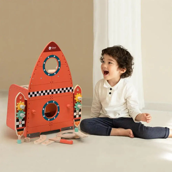 Smiling child playing with a wooden space-themed rocket workbench tool set indoors