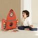 Smiling child playing with a wooden space-themed rocket workbench tool set indoors