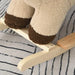 Close-up of brown plush rocking horse lion legs on wooden rocker base, striped carpet underneath