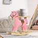 Pink and white plush rocking horse toy with wooden base in a modern nursery setting