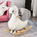 White and grey plush swan rocking horse with crown and safety seat in a cozy kids room