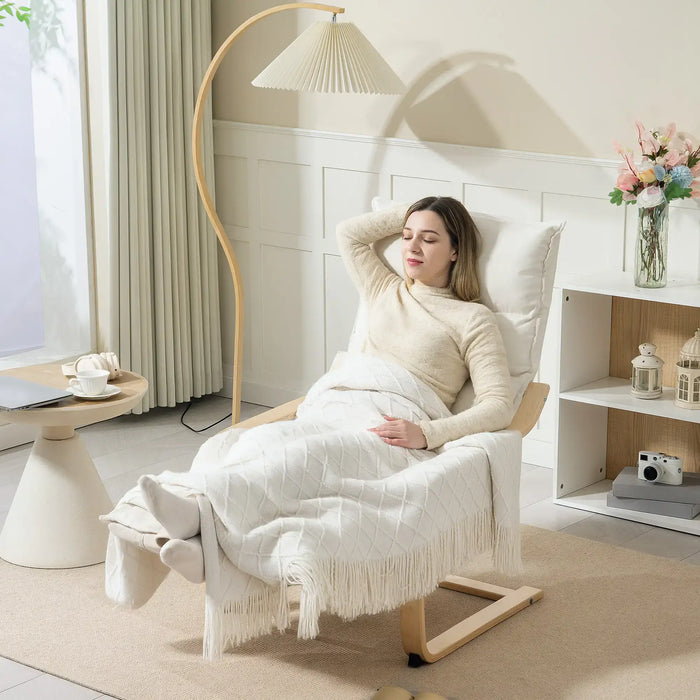 Woman relaxing in a chair with a white blanket in a cozy room.