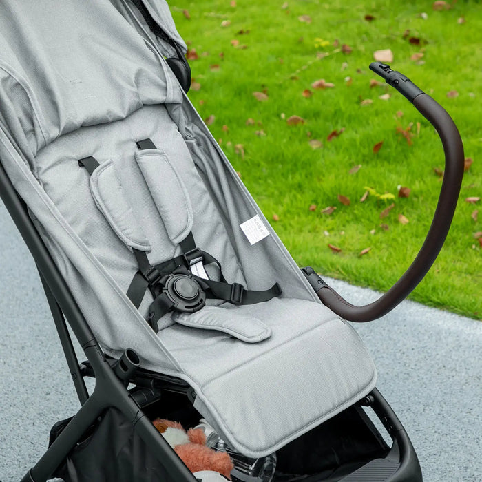 Gray stroller seat with black straps on a grassy background