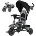 Gray and black children's tricycle with canopy attachment on a white background