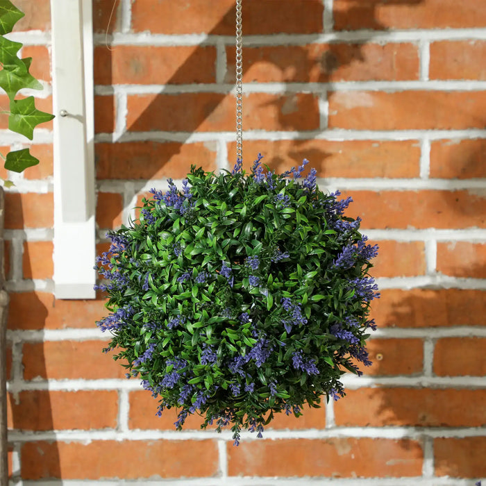 Hanging basket with green foliage and purple flowers against a brick wall