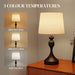 Table lamp with three color temperature options displayed on a wooden surface.